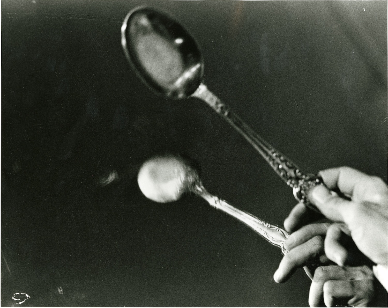 Photograph of a performer’s hand tapping a spoon against a mirror