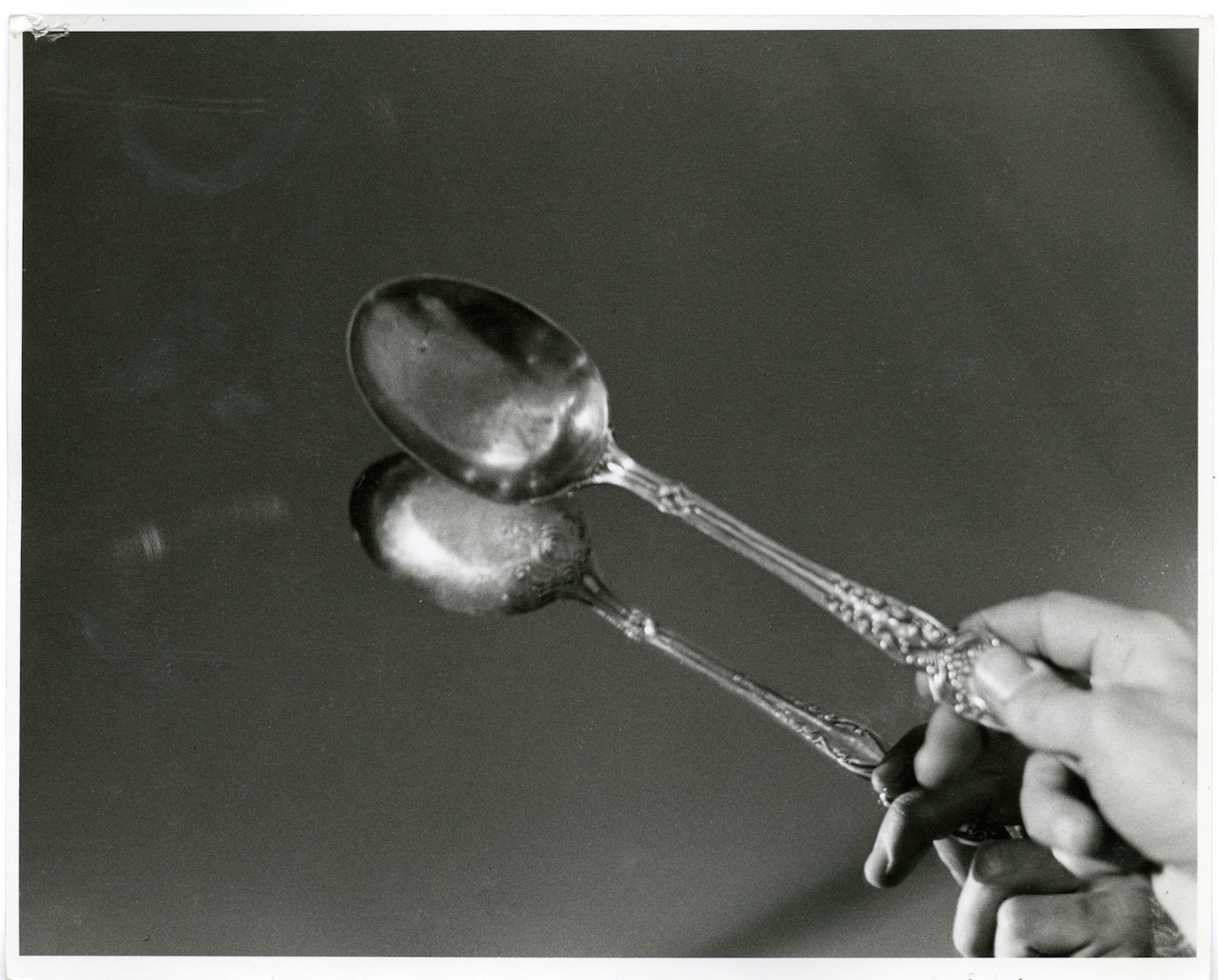 Photograph of a performer’s hand tapping a spoon against a mirror