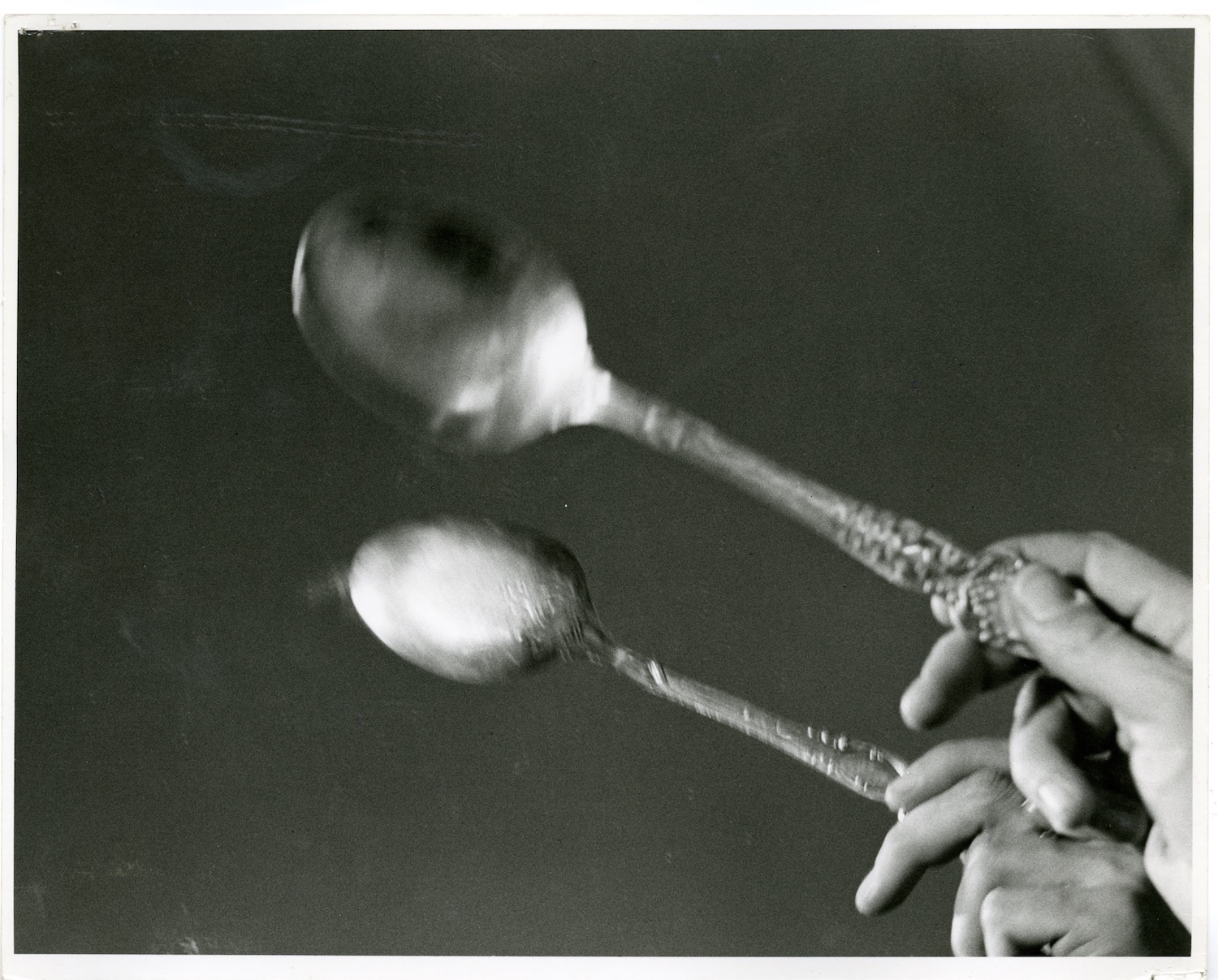 Photograph of a performer’s hand tapping a spoon against a mirror