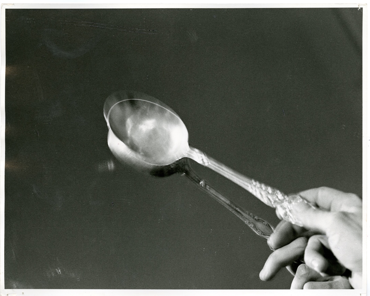 Photograph of a performer’s hand tapping a spoon against a mirror