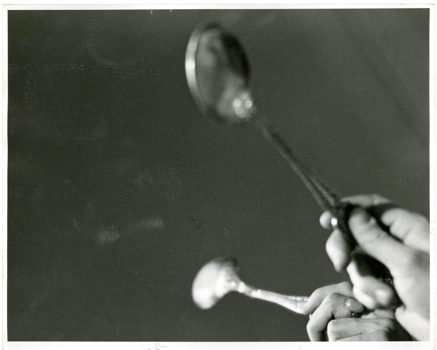 Photograph of a performer’s hand tapping a spoon against a mirror