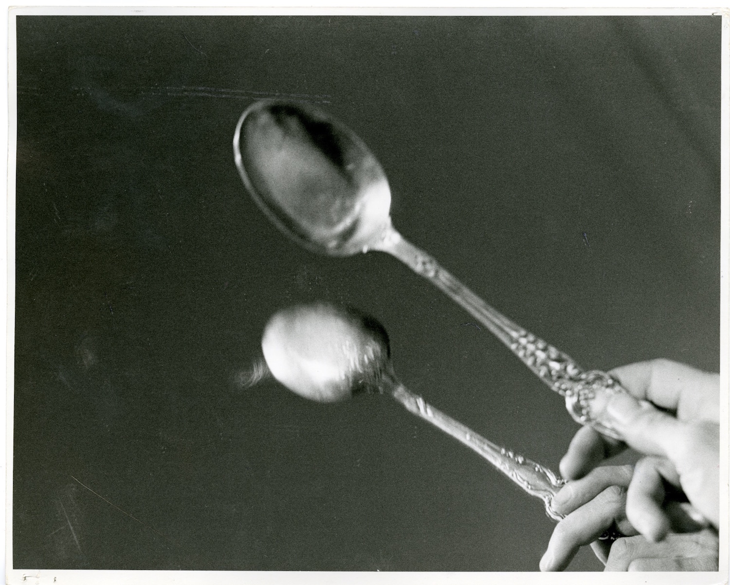 Photograph of a performer’s hand tapping a spoon against a mirror