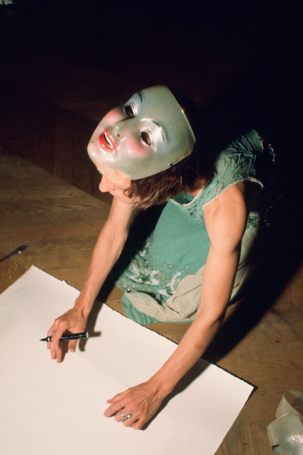 Jonas sitting on the floor with her mask pulled up, about to draw on a piece of paper