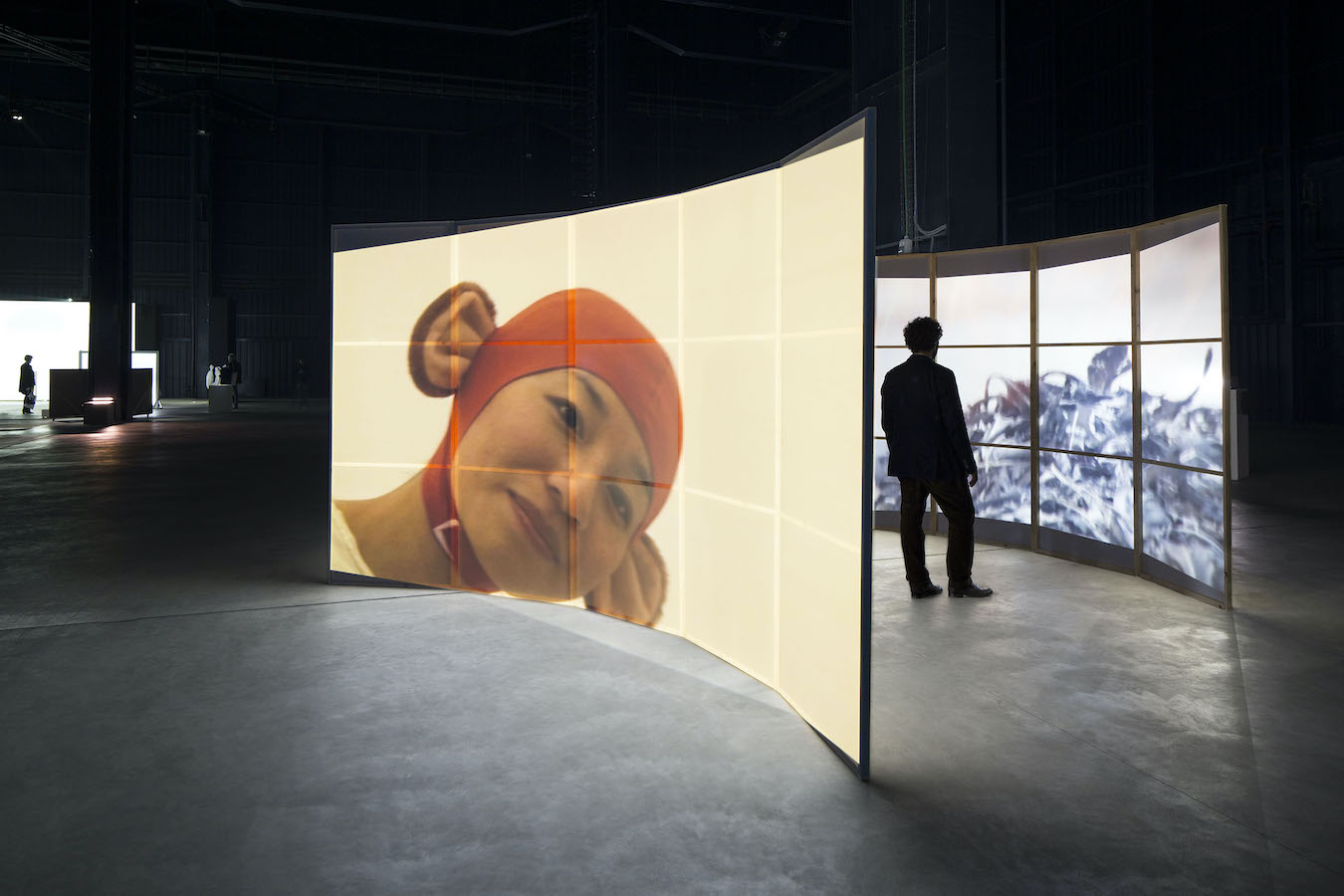 A figure stands in between two curved screens to watch a video projection