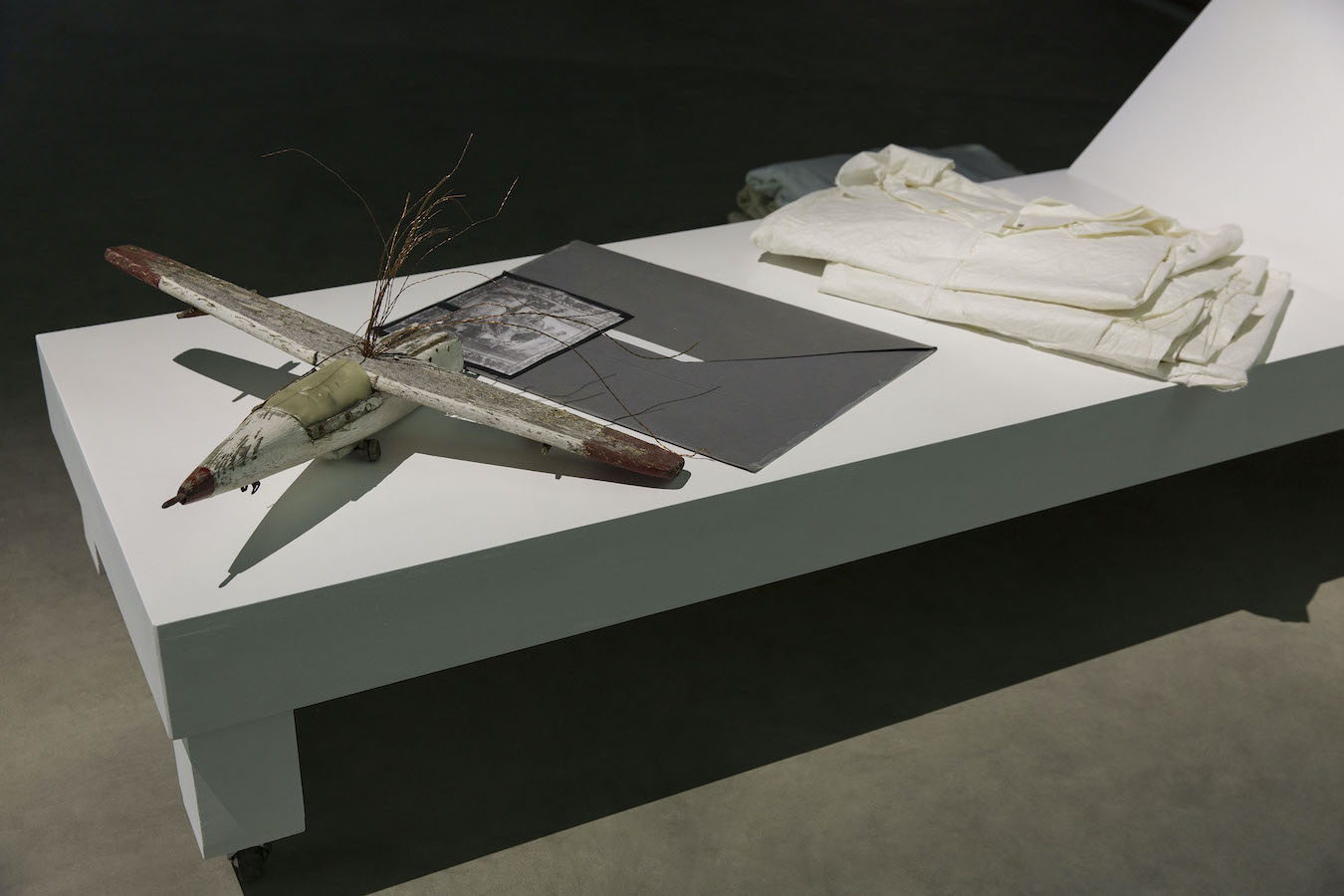 A model plane, a large envelope, and folded clothes are placed on a lounge chair.