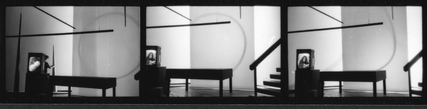 Three photographic frames from Jonas’s performance set. In the room there are two large cones, a TV monitor on a stand, a table, a staircase and a white backdrop with shadows on it.