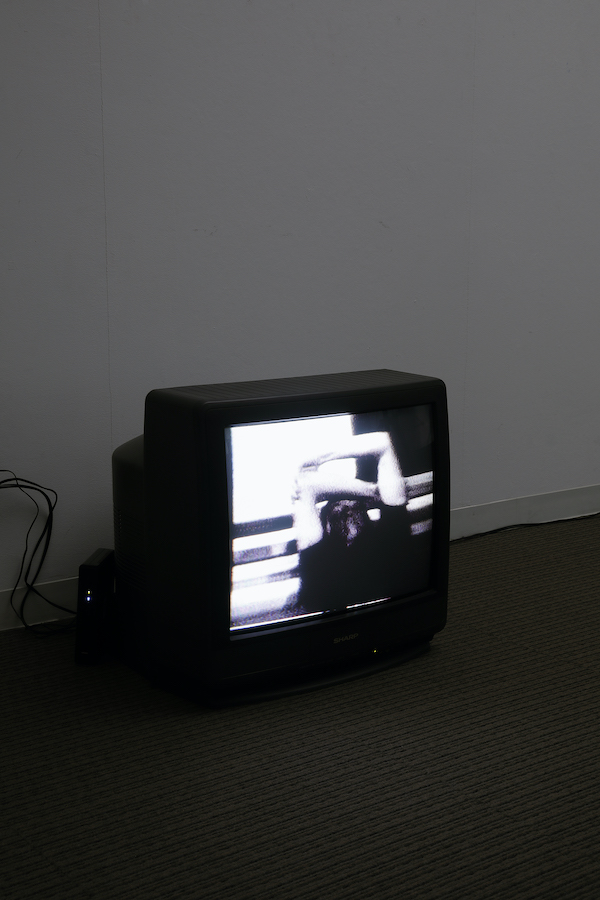 A TV monitor on the floor displaying a performer holding their arms.