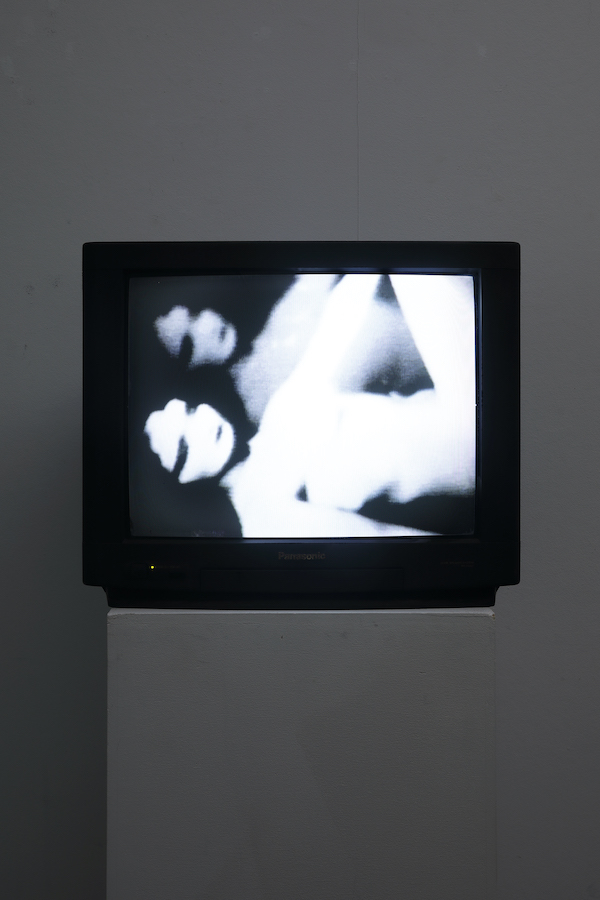 A TV monitor on a stand displaying a double image of a female figure.