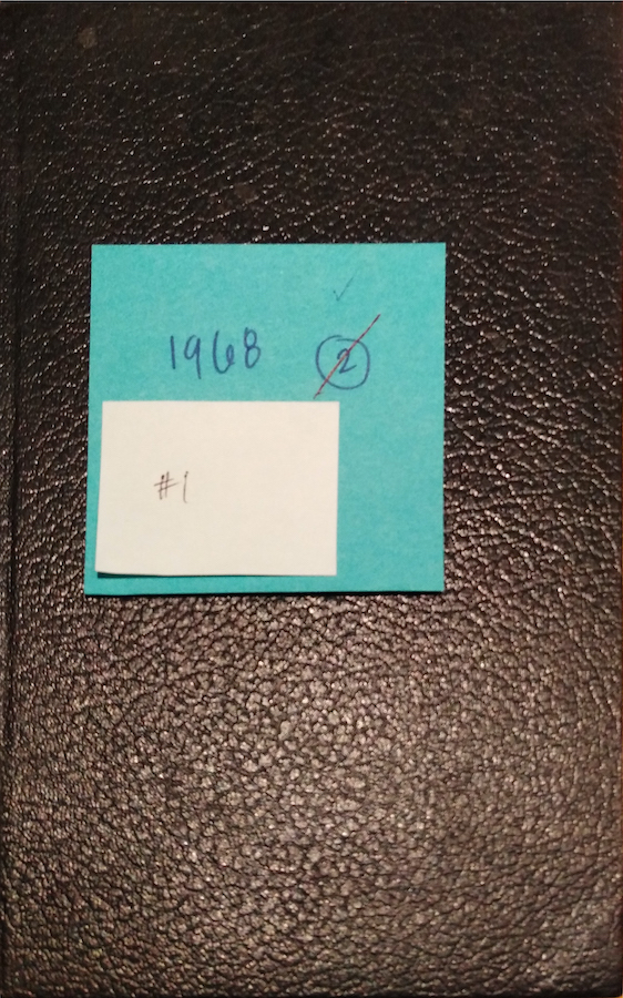 Notebook cover with a small sticky note that reads: “#1” on top of a larger sticky note that reads: “1968. 2.” the number “2” is circled and crossed out.