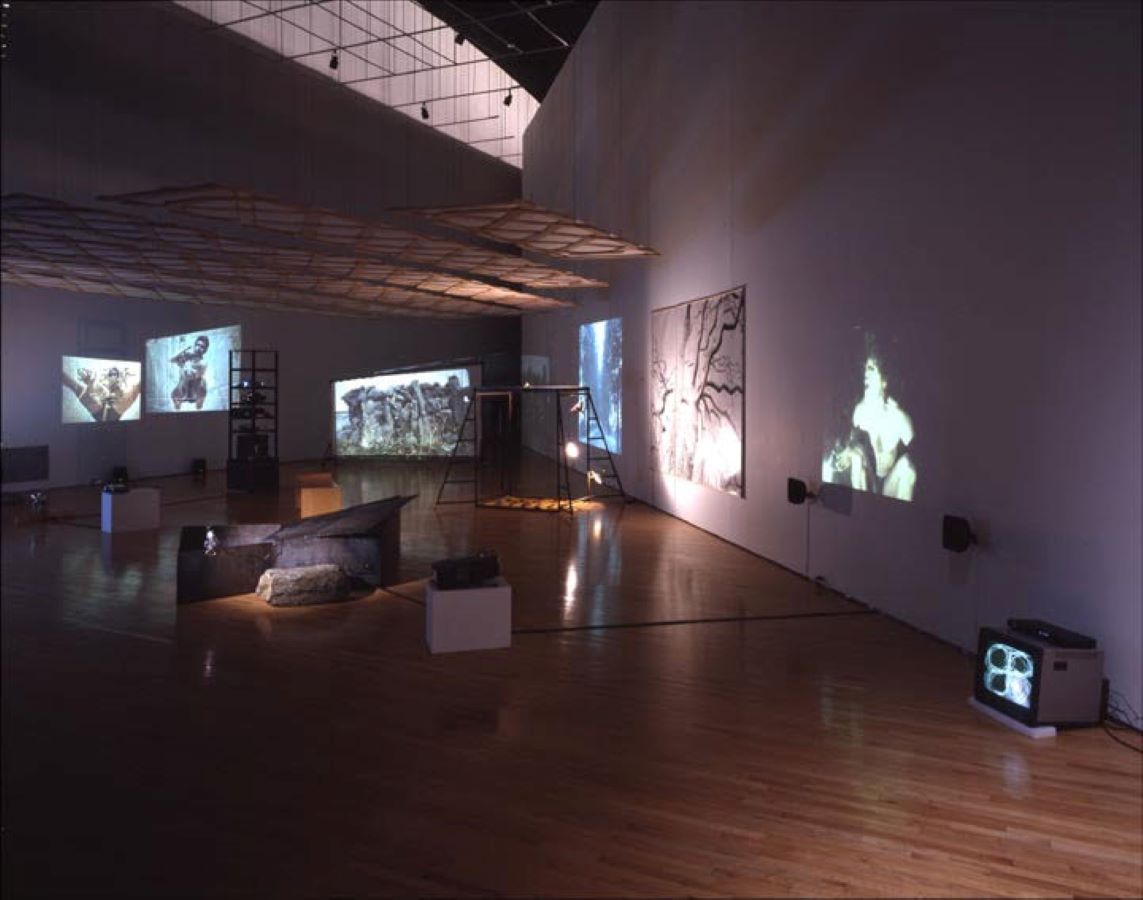 A room filled with various props, video projections, and a TV monitor