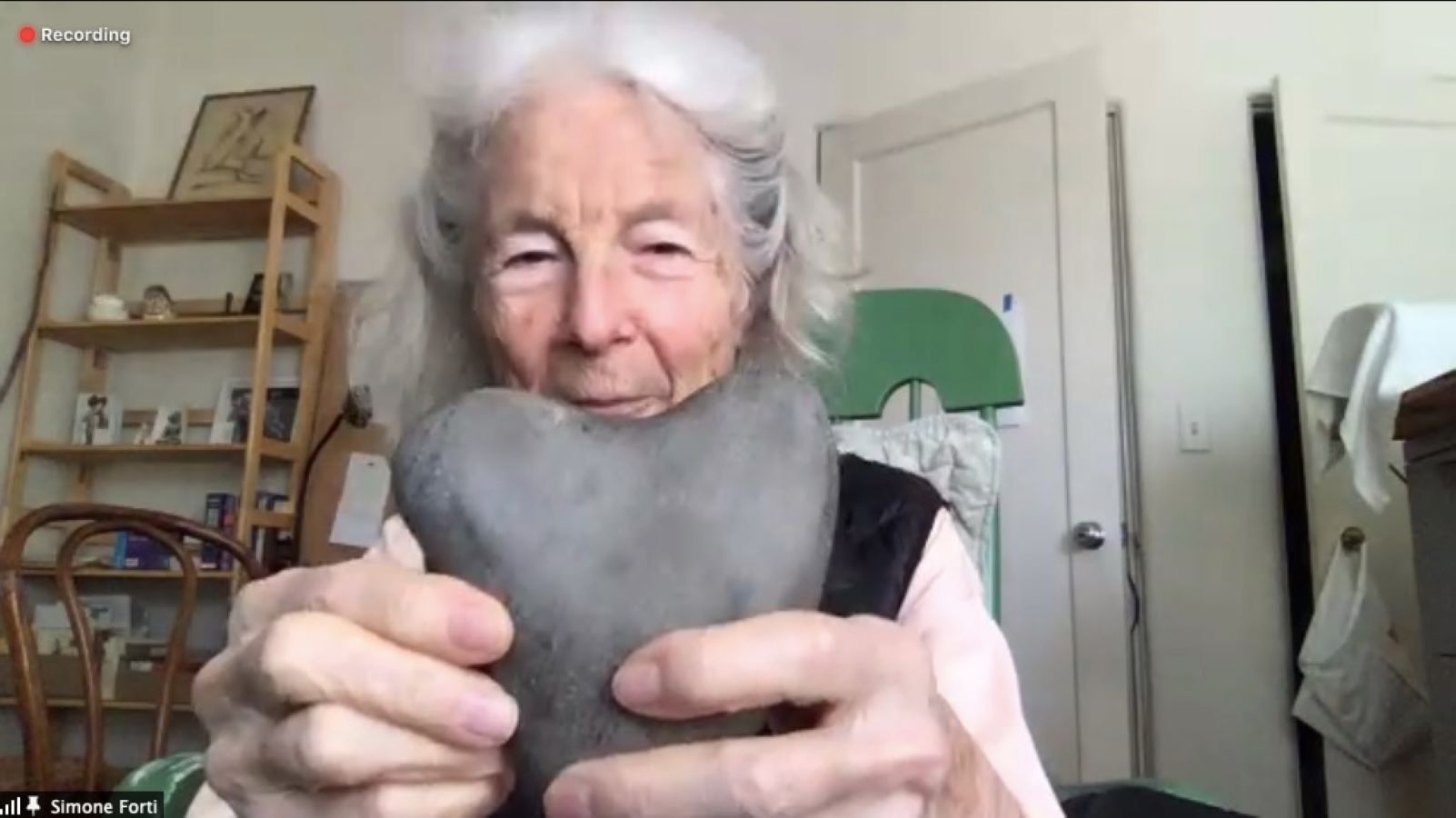 A woman holding up a rock in the shape of a heart.